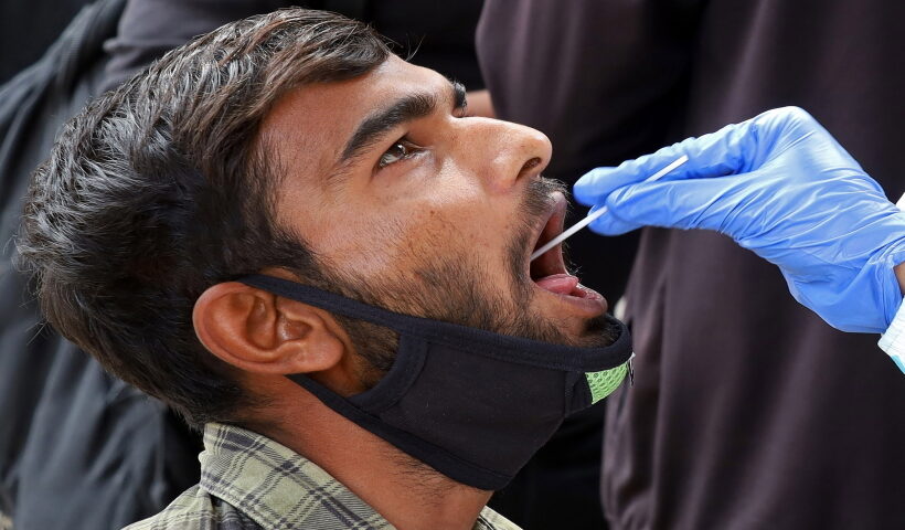 A health worker collects swab samples of a passenger for COVID-19 test