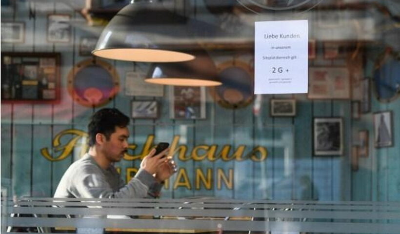 A customer waits to be served at a restaurant with a sign notifying people of the "2G+" anti-epidemic rules against COVID-19 in Frankfurt, Germany,