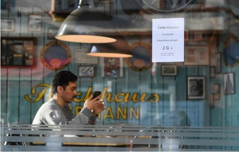 A customer waits to be served at a restaurant with a sign notifying people of the "2G+" anti-epidemic rules against COVID-19 in Frankfurt, Germany,