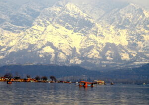 Srinagar: A boatman rows his shikara in Dal Lake as the mountains are covered with snow in Srinagar