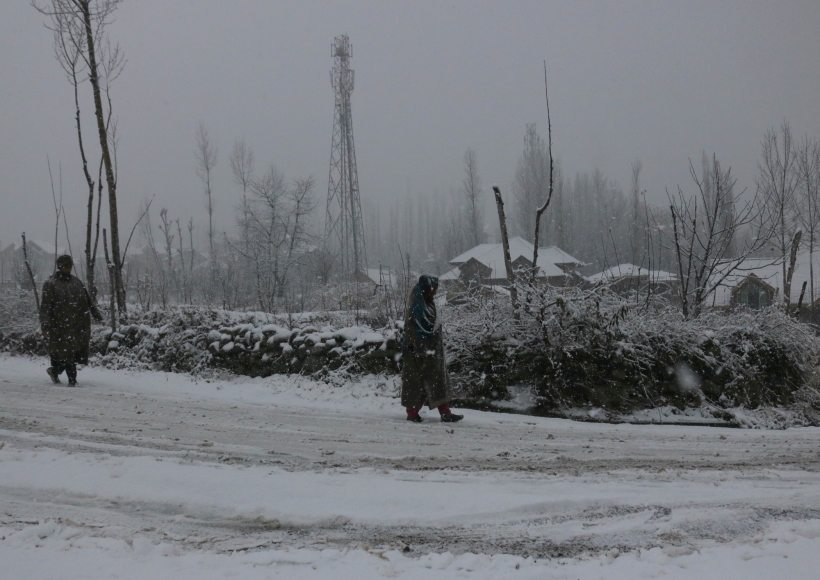 Srinagar:Kashmiri people walk through snow covered road in Srinagar