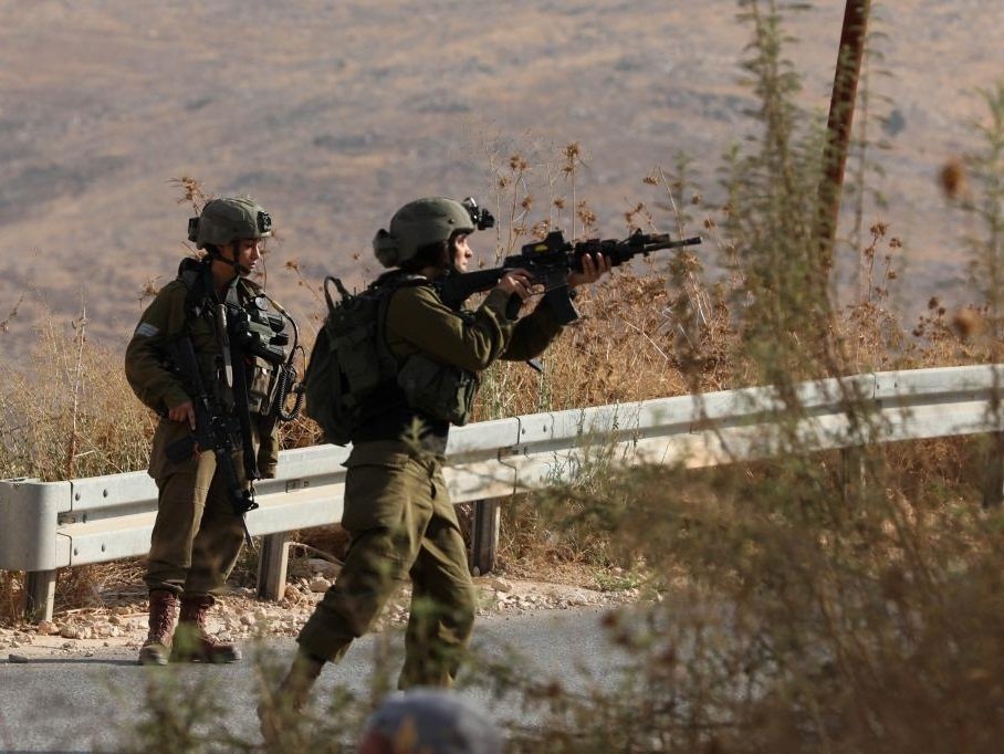 Israeli soldiers close a road after a shooting attack on an Israeli bus