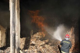 A rescuer battles a building fire in central Baghdad