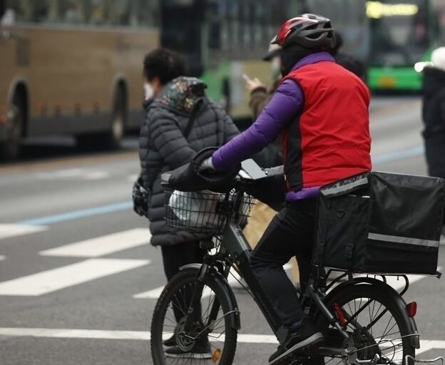A delivery worker crosses a street in Seoul