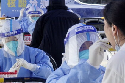 A medic takes swab samples from a resident for nucleic acid testing at Balizhuang subdistrict in Chaoyang District, Beijing