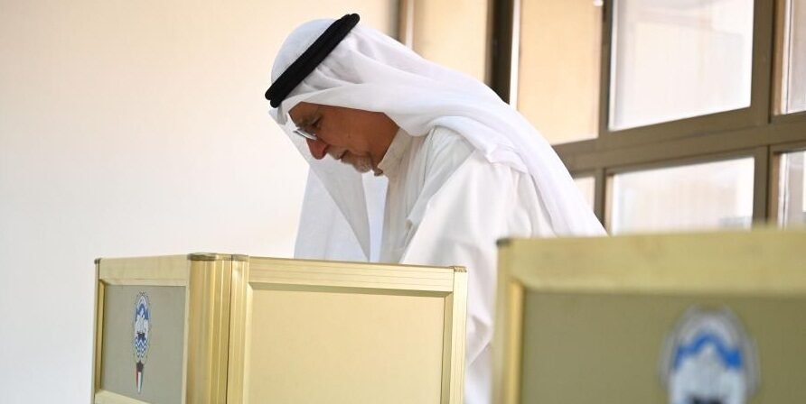 A man fills in his ballot paper at a polling station in Capital Governorate, Kuwait